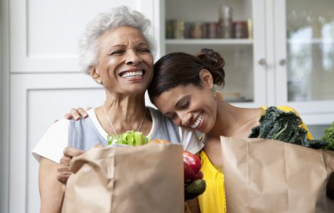 Mother and daughter unpacking groceries in kitchen